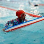 image shows a girl in a red hat on a float in a swimming pool image shows a girl in a red hat on a float in a swimming pool