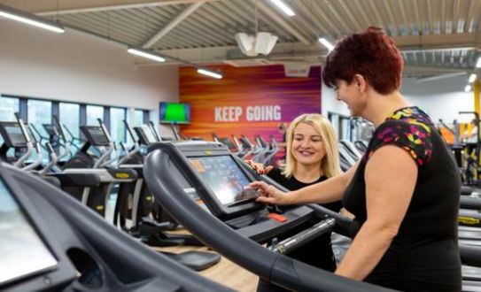 Staff member helping gym member on the treadmill