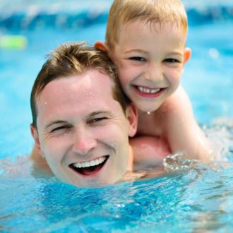 man and boy playing and smiling in pool