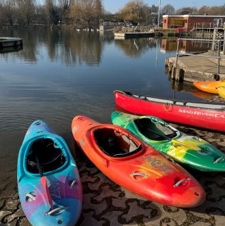 several brightly coloured kayaks lined up along the edge of Stanborough LAke