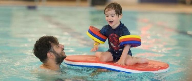 adult and child playing with a float in a pool