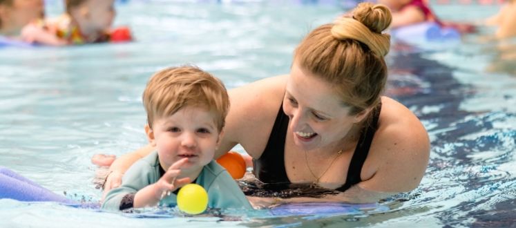 Adult and Child playing in the swimming Pool with floats.