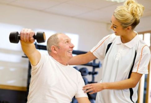Instructor assisting male with correct technique for using hand weights
