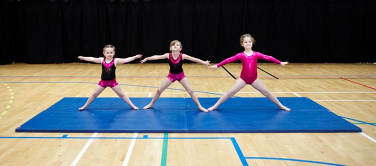 image shows three girls in a gymnastics pose