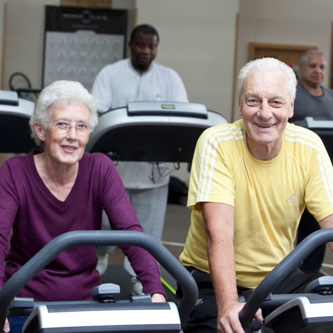 senior couple cycling in gym