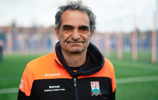 Man on a football team wearing a black and orange jacket