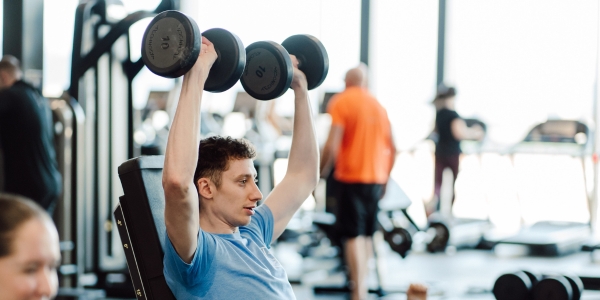 A man working out at the gym using dumbells 