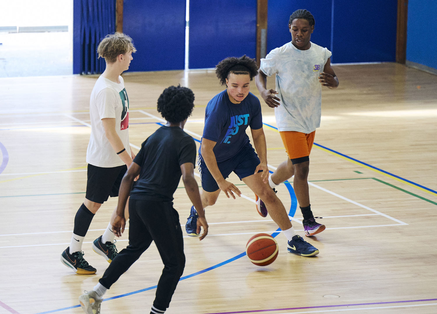 group of young males playing basketball on an indoor court