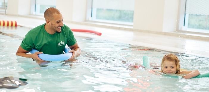 Child using a pool noodle to practice in a swimming lesson