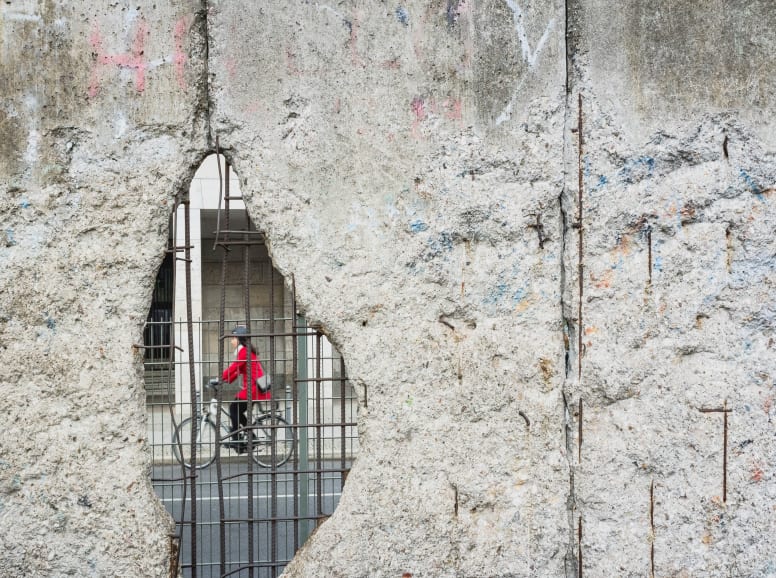 A Hole in the Old Berlin wall with a Cyclist Visible on the other Side