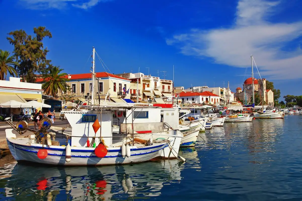 Boats in harbor with church in background in Aegina