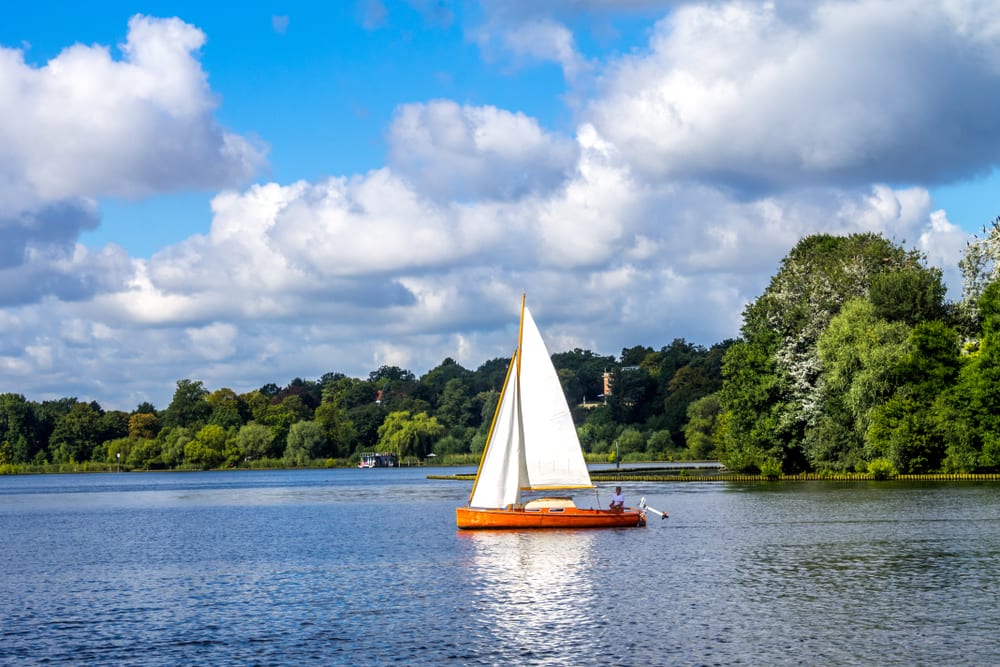 A Mini Sailboat With a White Sail on a Lake 