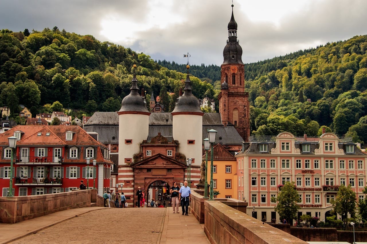 a Bridge Leading to Gabled Houses and a Church Near a Hill