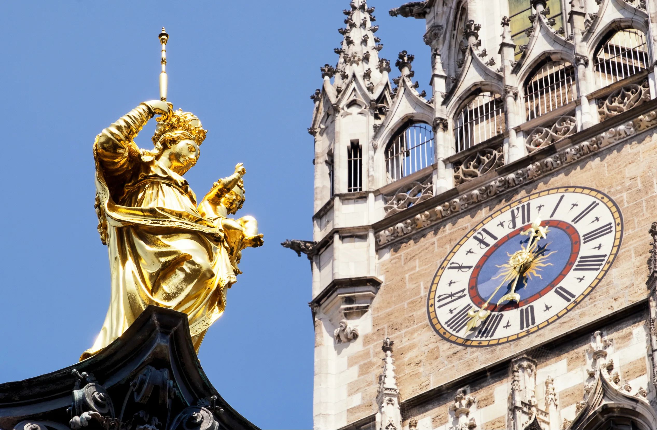 A Gold Plated Statue of a Woman in Front of a Clocktower