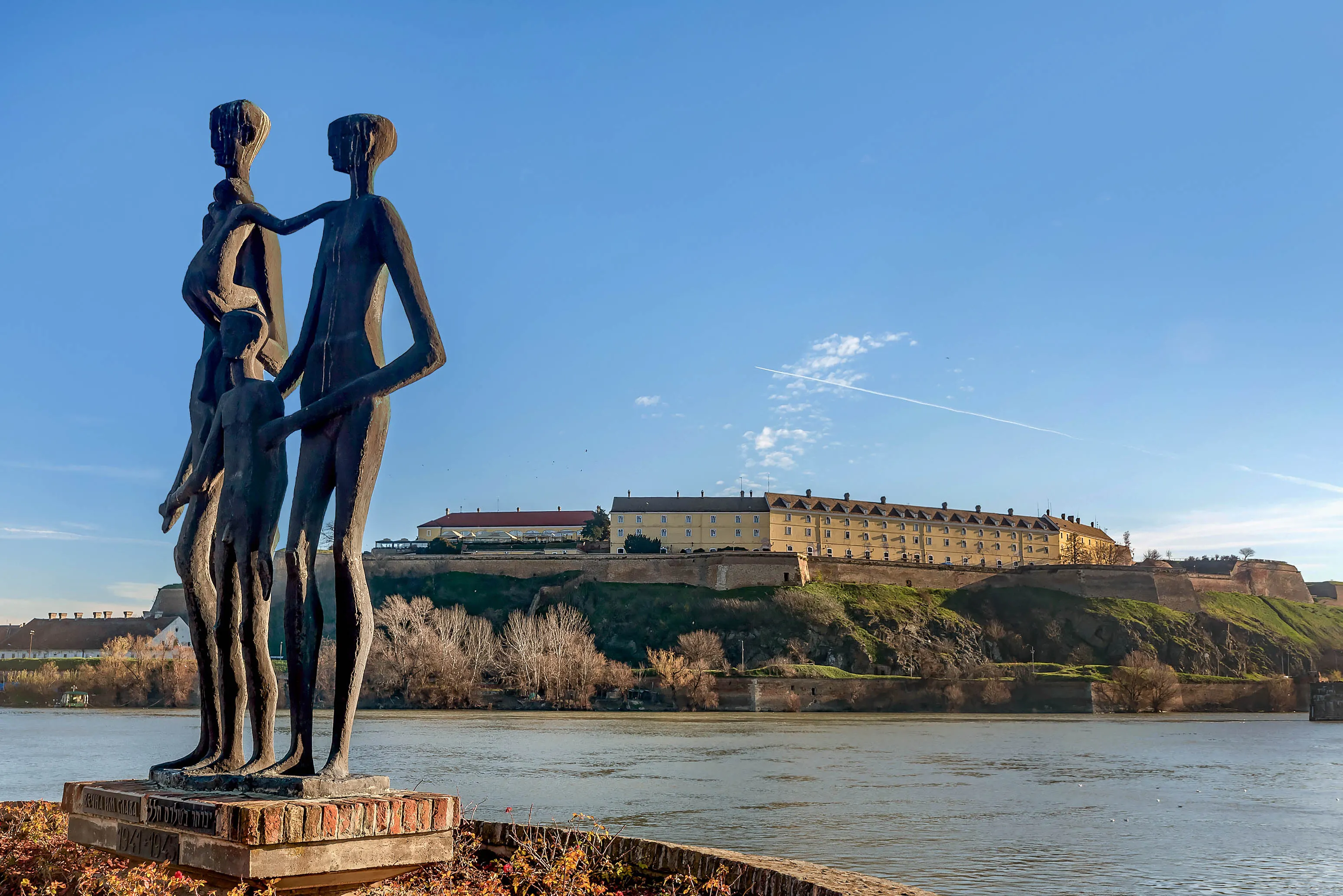 Statue of Three Figures Standing next to a Rivera Shore