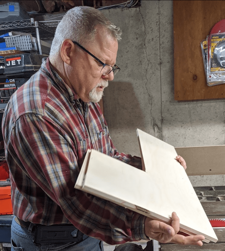 Picture of Dr. James P. Walden inspecting some baltic birch wood cut into L shapes