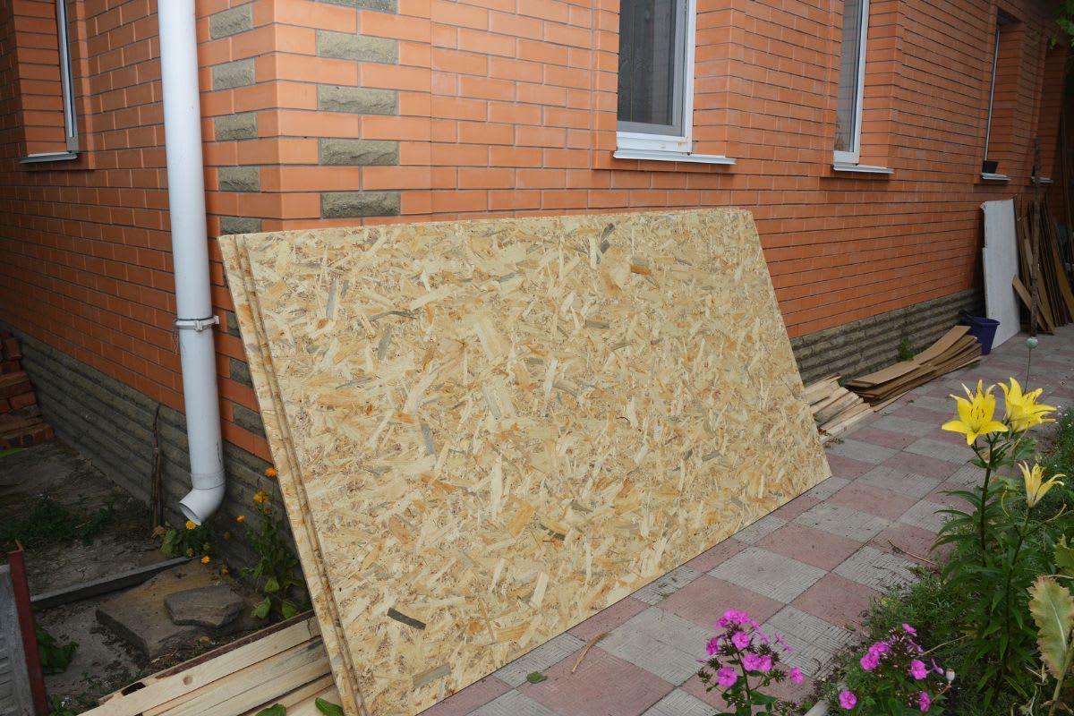 OSB-Platte lehnt außen an einem Haus, um vor der Verarbeitung zu akklimatisieren.