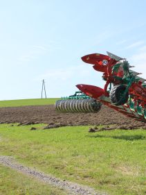 Packers - Kverneland Packomat compact and transported above ground level, dragged by tractor in a folded shape