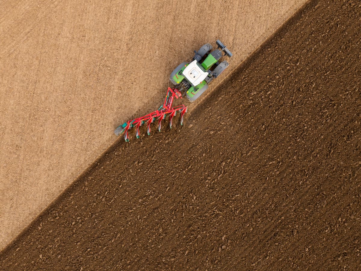 Detail view of Kverneland 3400 B Variomat plough working the soil behind a tractor