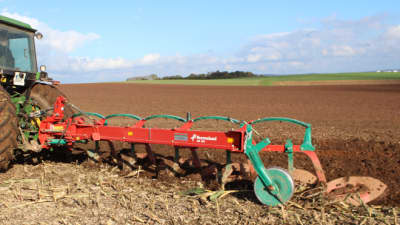 Charrue conventionnelle Kverneland AB au travail dans un champs vue de côté