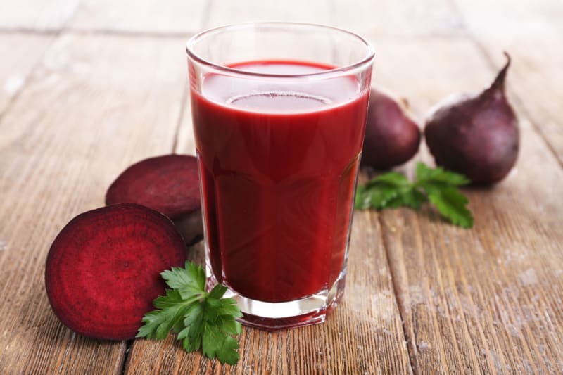 beet juice in glass on wood table with beets