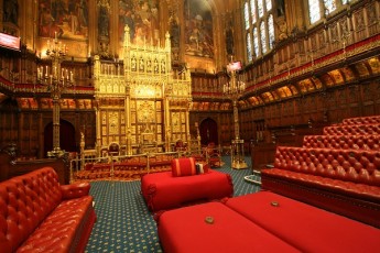 The House of Lords at Westminster. The Throne is seen at the back. In front of the Throne is the Woolsack, which is where the presiding Lord Speaker sits. Before 2006, a government minister, the Lord Chancellor, presided over the House. UK Parliament via Flickr, published under Creative Commons.