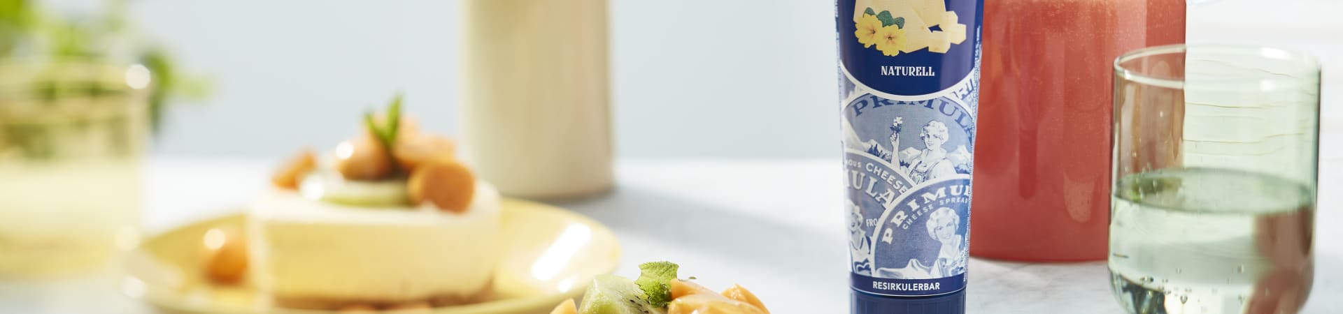 Sitronostekake i porsjoner, toppet med kiwi, physallis-frukt og en frisk, gul saus