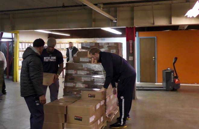 Notre Dame players Shaun Crawford (right), Justin Ademilola (middle) and Liam Eichenberg (right) unload pork productions Indiana Gov. Eric Holcomb won in a bet on the Camping World Bowl.