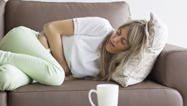 woman on couch with stomach pain