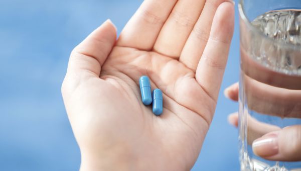 woman with blue pills in palm of hand