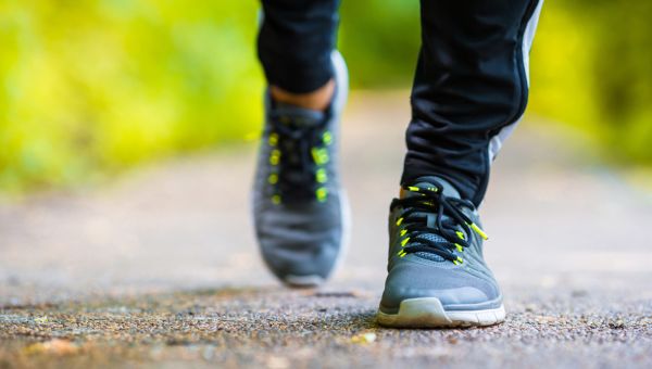 view of feet in gray sneakers walking toward the camera outdoors