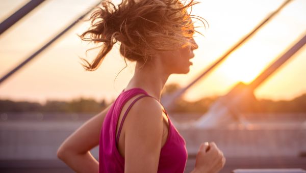 woman running across bridge at sunrise