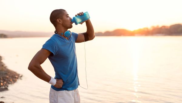 man drinking from a water bottle outside