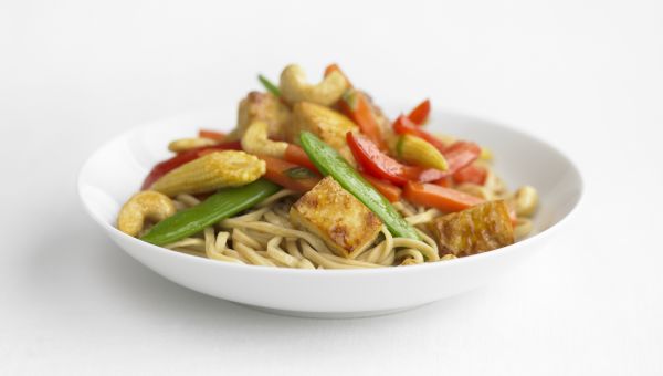 Stir-fry with noodles in a white dish, close up