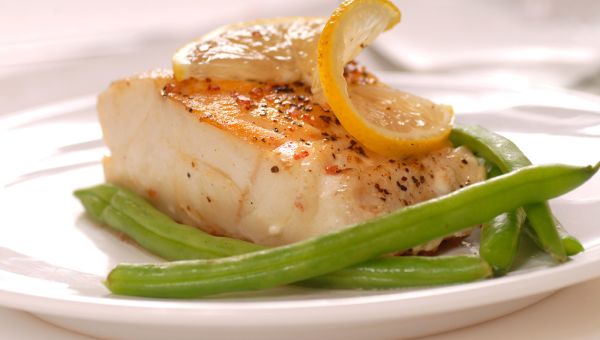 grilled white fish on a white plate with green beans