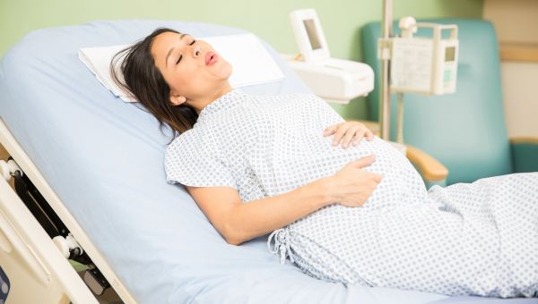 pregnant woman experiencing contractions on hospital bed