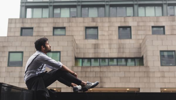 man sitting on ledge in city