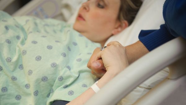 woman giving birth, holding hand, hospital bed