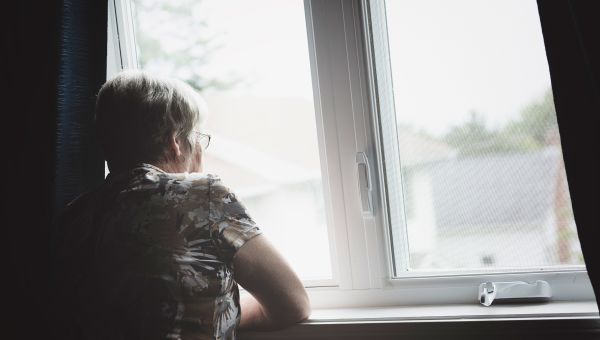 lonely senior woman staring out of window