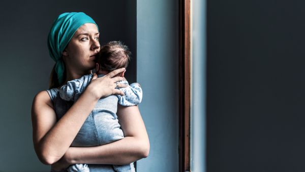 Someone holding infant while looking out towards window