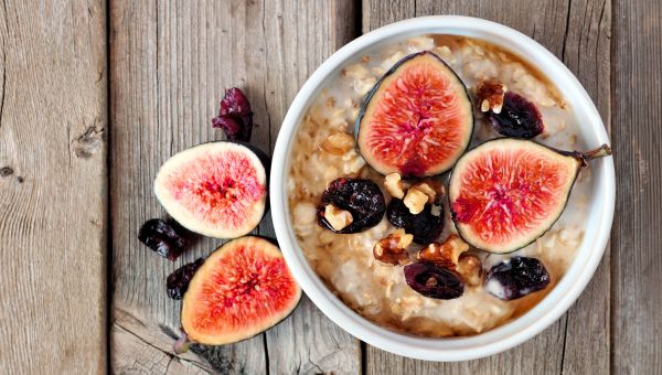 Oatmeal with figs, cranberries and walnuts on wooden table