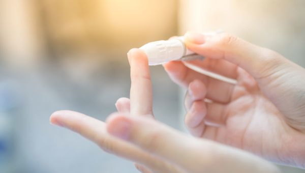 Someone using glucose meter to measure blood sugar levels