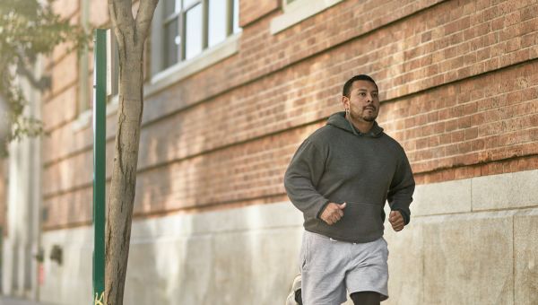 Man running outside in sweatshirt and headphones