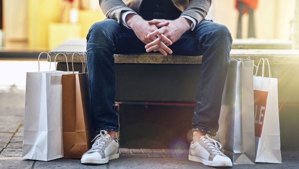 Man sitting on bench surrounded by shopping bags
