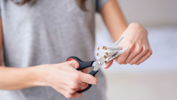woman cutting cigarettes in half with scissors