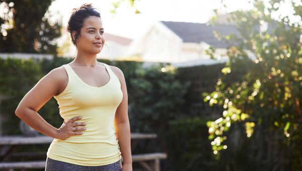 woman standing outside, exercising. 