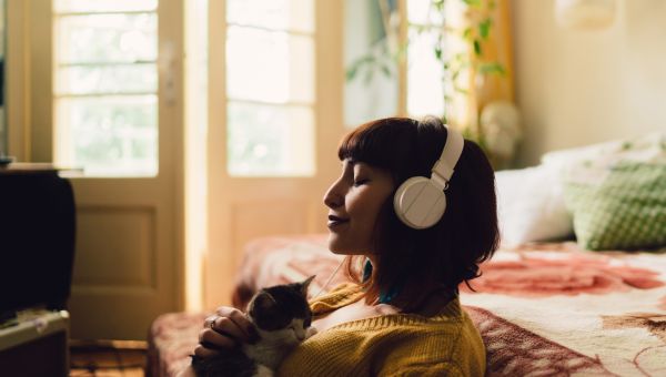 young woman listening to music with her cat