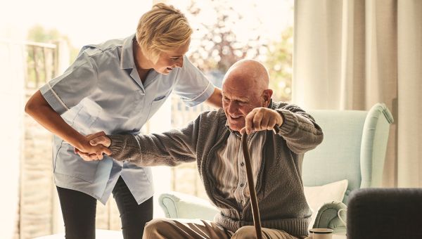 nurse helping man with cane