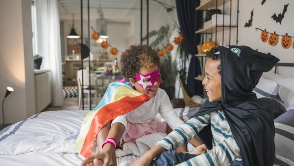 Two kids in costumes celebrating Halloween at home