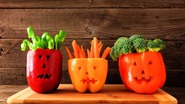 Jack-o-lanterns cut out of bell peppers and holding veggies